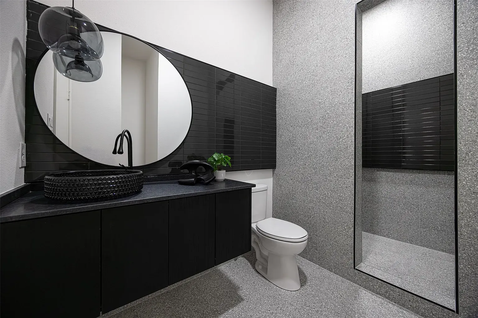A modern bathroom with an oval mirror and black vessel sink