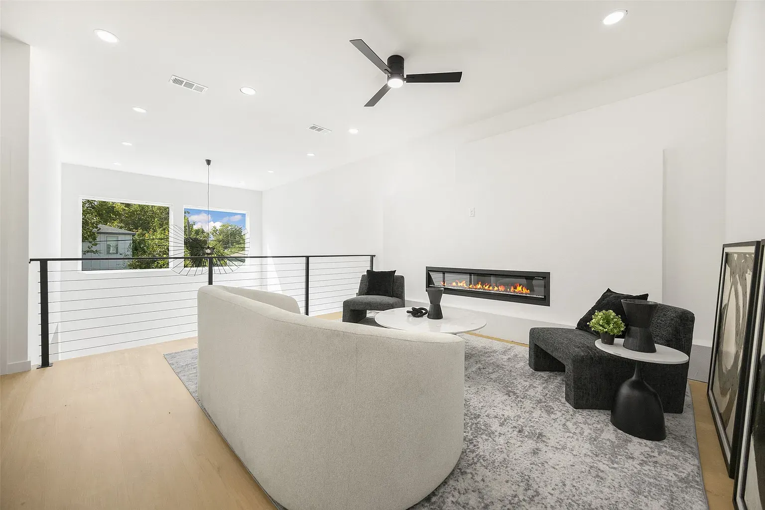 A bright living room with white sofas and a linear fireplace