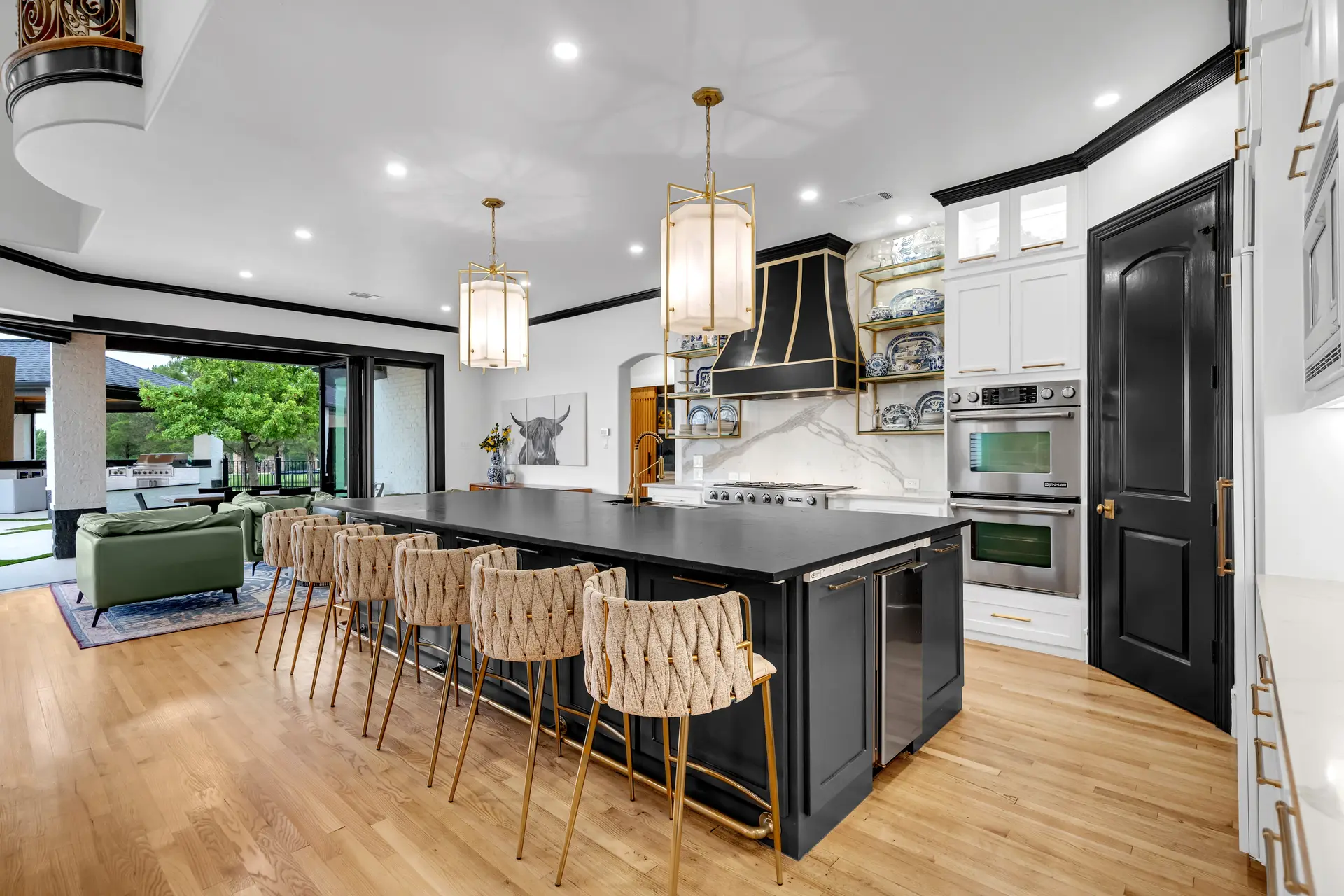 An open kitchen with a long black island and warm wood floors
