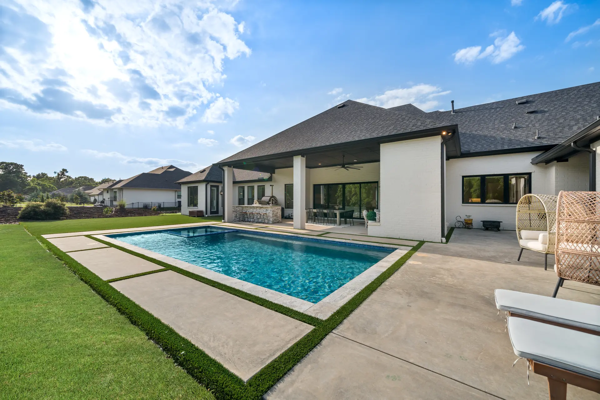 A white brick home with a backyard pool and patio on a sunny day