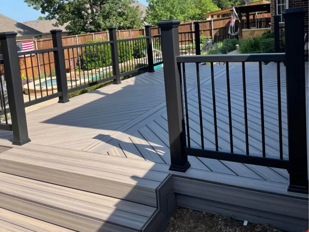 Composite deck with black aluminum railing beside a backyard pool