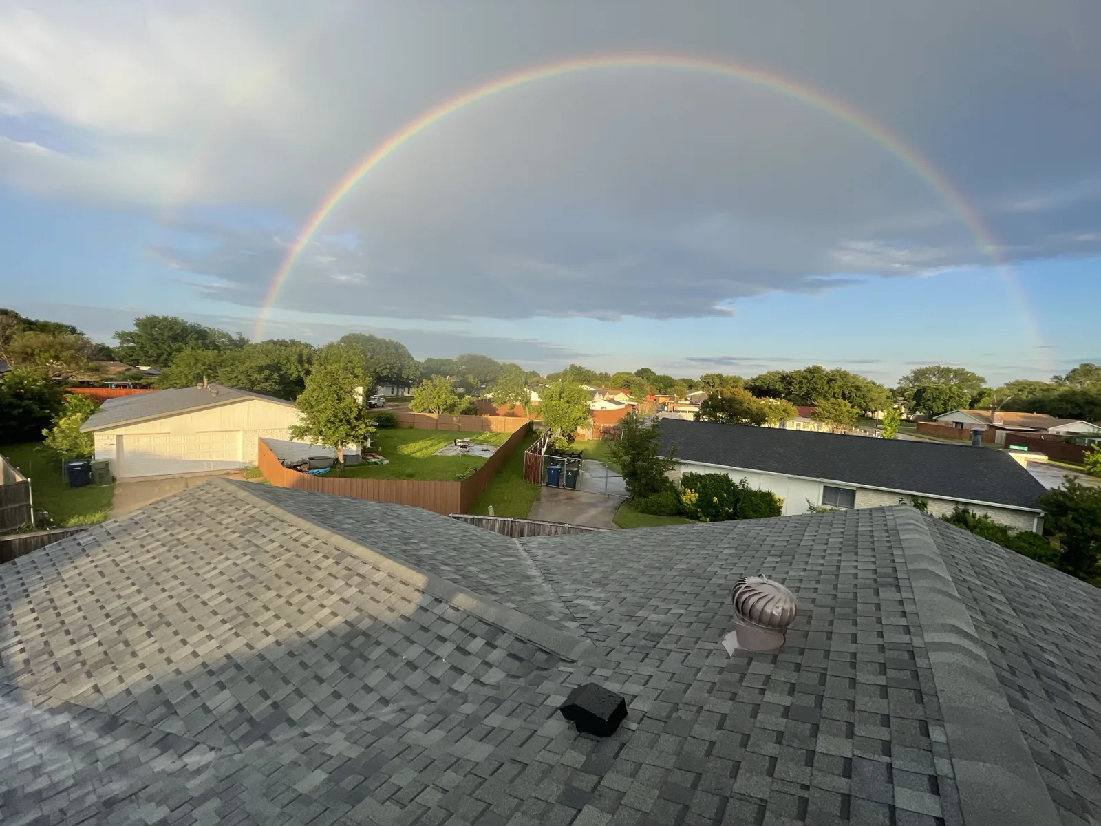 Finished shingle roof over a newly built patio with a rainbow in the sky