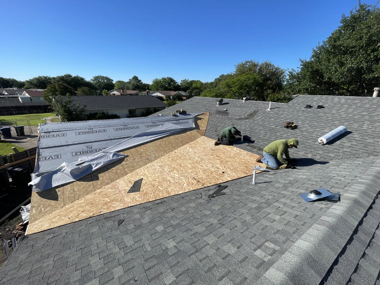 Roofers installing new decking and underlayment over a patio roof section