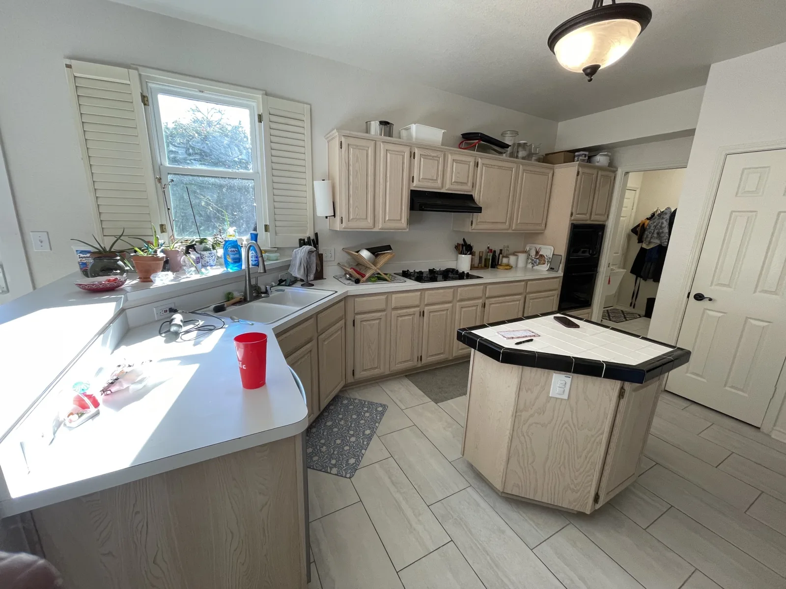 Original Rowlett kitchen with light oak cabinets, white laminate counters and a tile-top island before remodeling